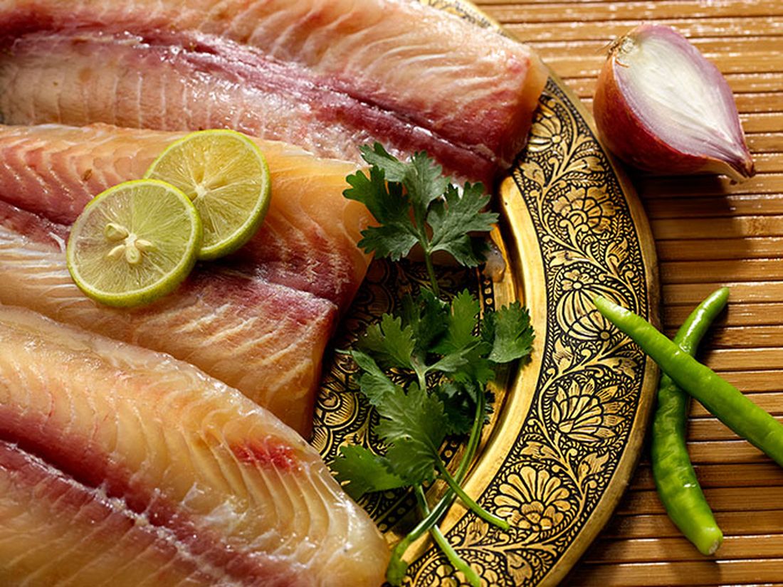 Fresh boneless Basa fillets with lime, coriander and green chilli on a brass plate